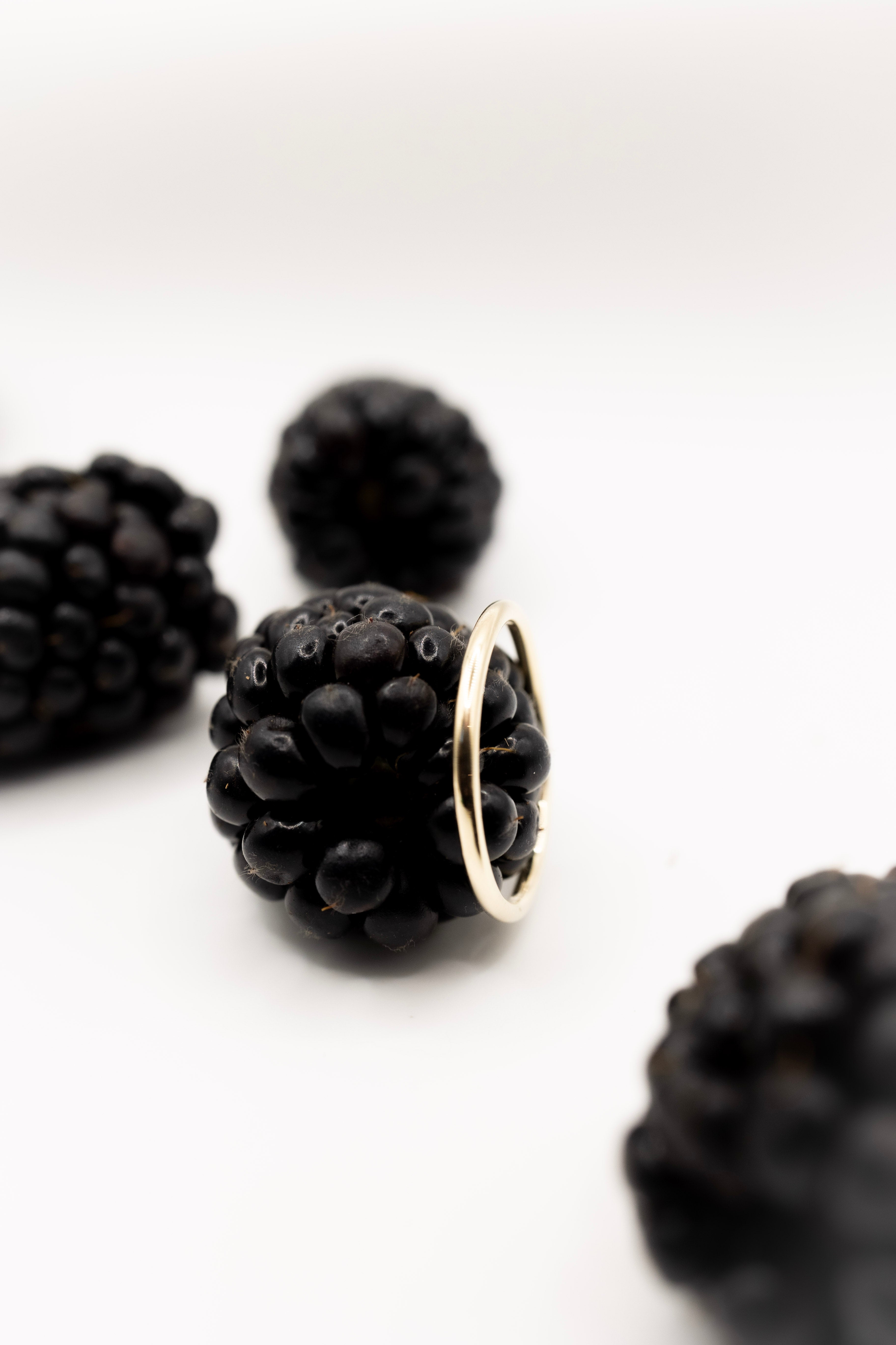 Blackberry with a solid gold ring on a white background