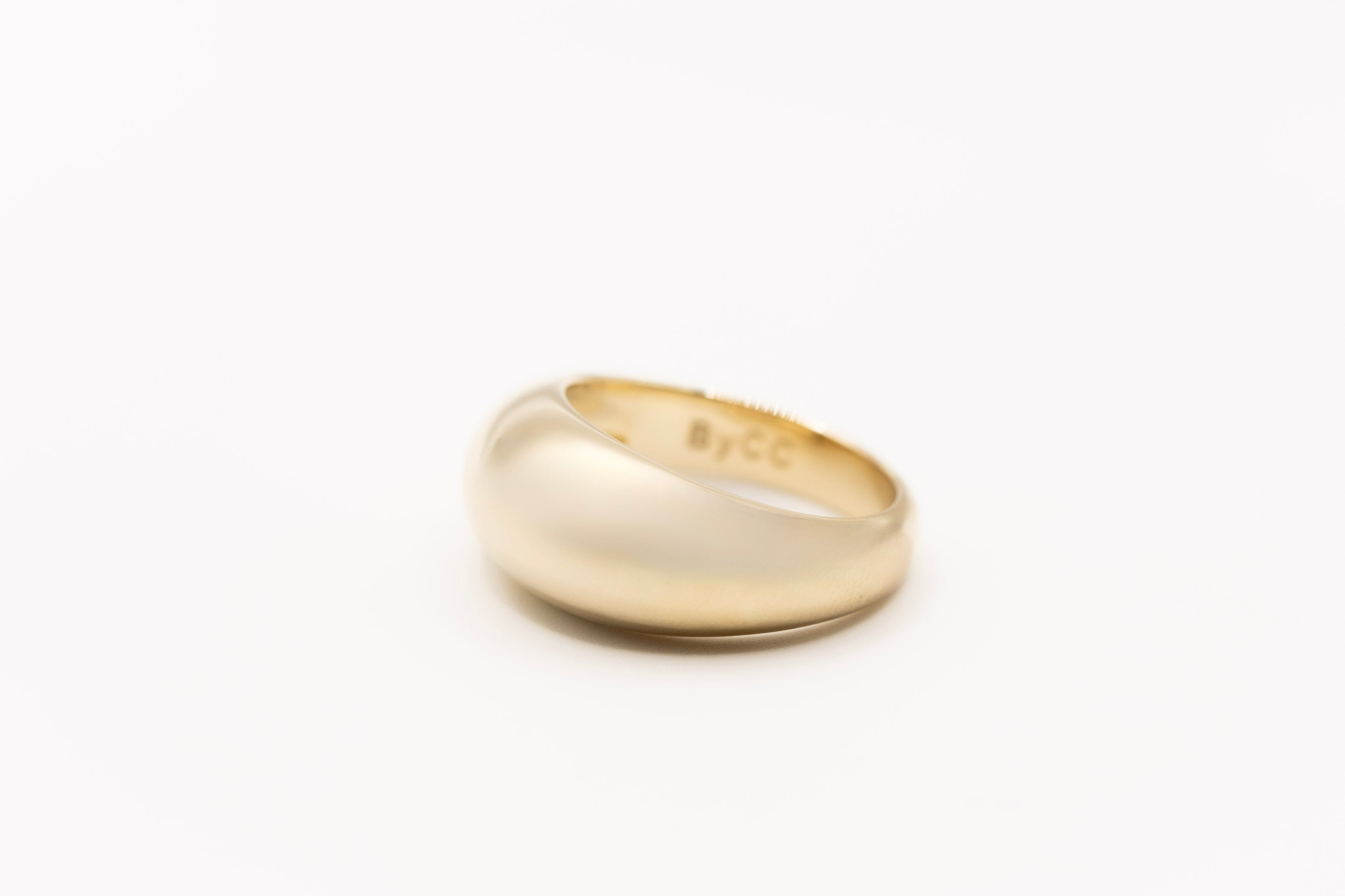 Solid gold dome ring on a white background