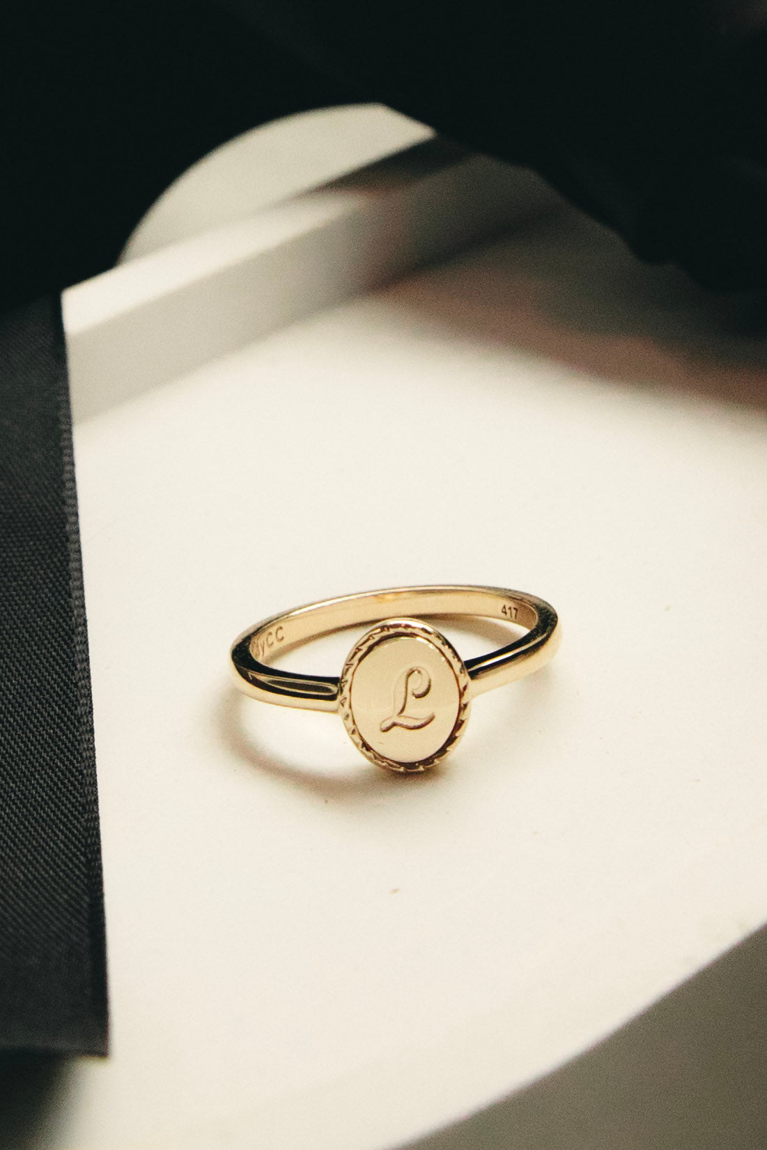Gold ring with a circular emblem on a white surface