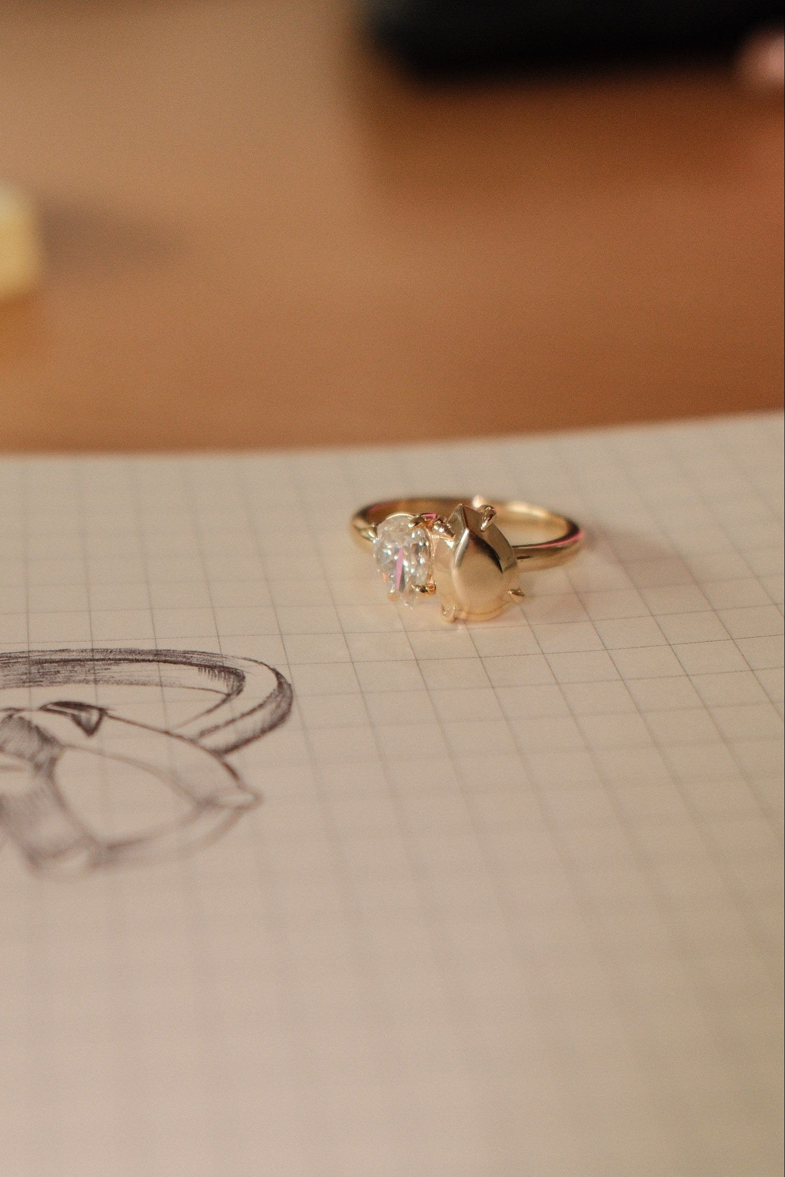 Gold ring with a diamond on a piece of paper with a drawing of a ring.