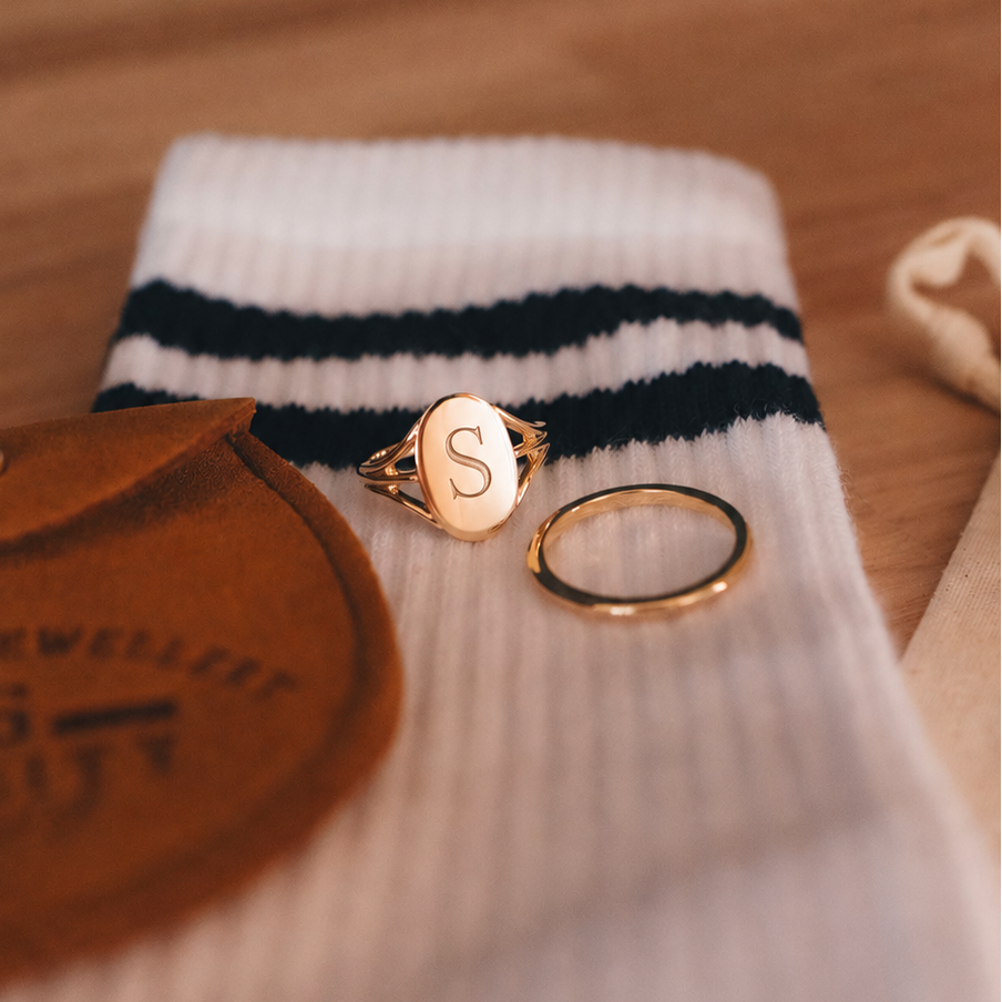 Gold rings on a white sock with black stripes on a wooden surface