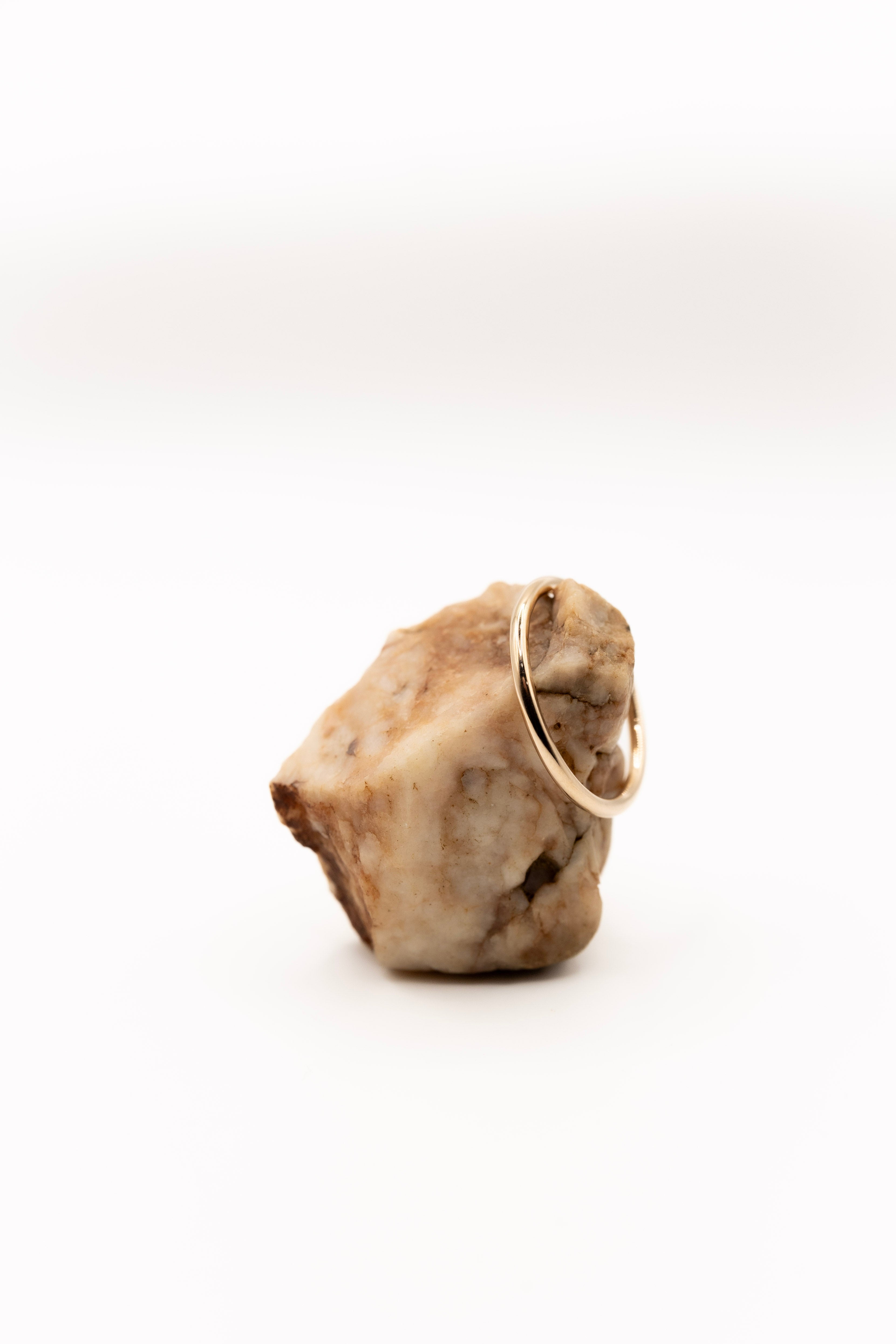 Gold ring on a rough stone surface with a white background