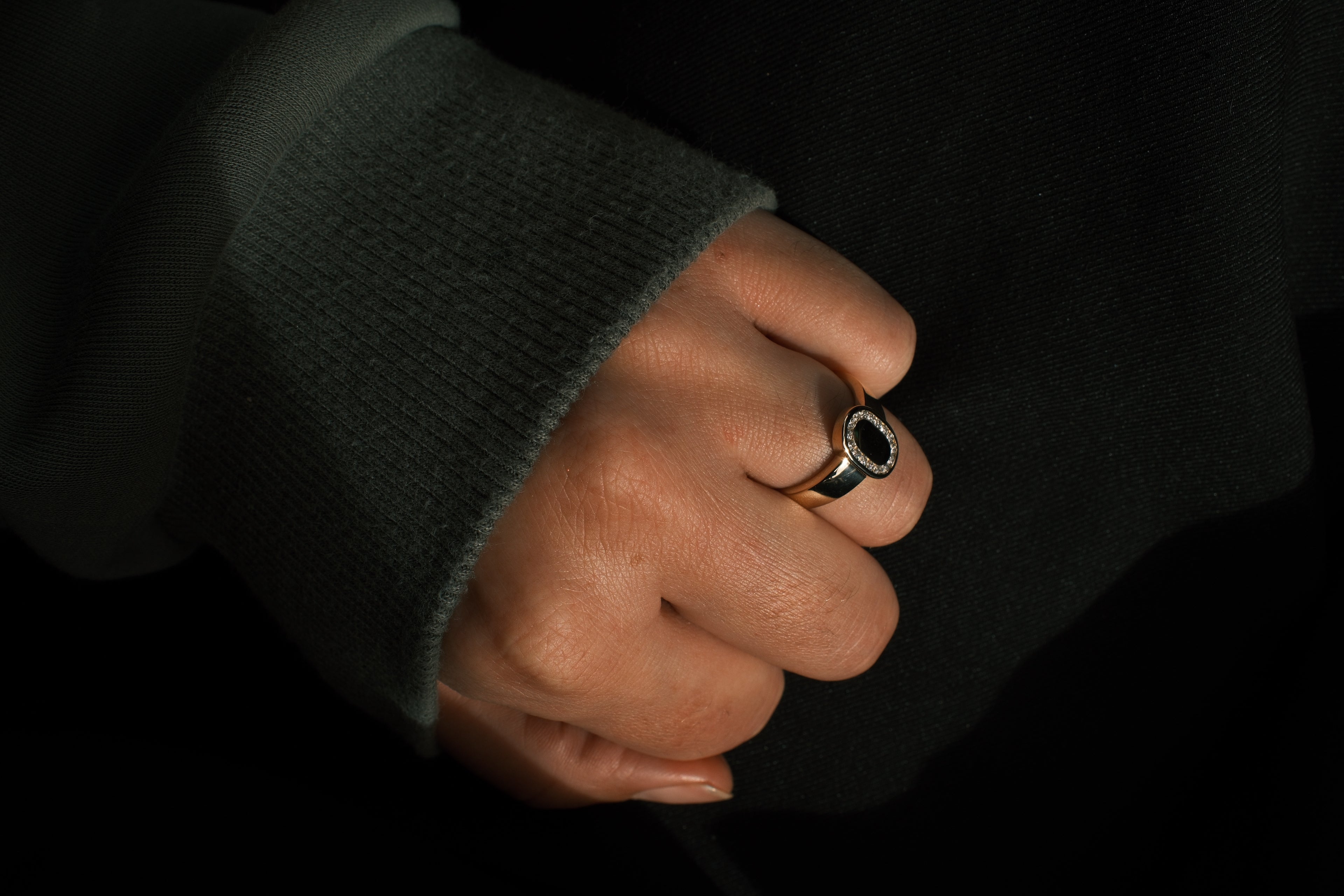 Hand wearing a ring with a dark background
