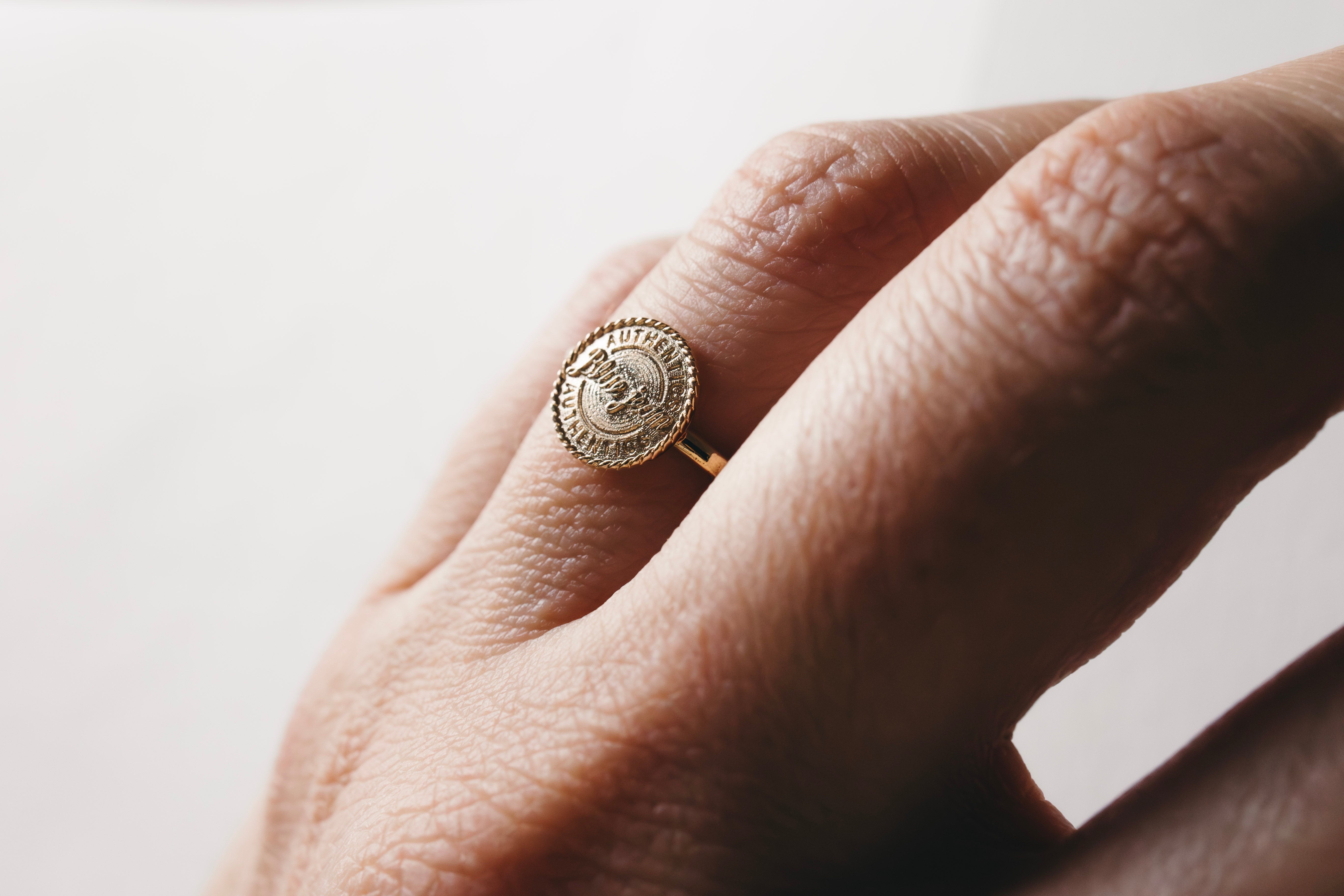 Aussie Gold ring with a circular design on a hand against a neutral background