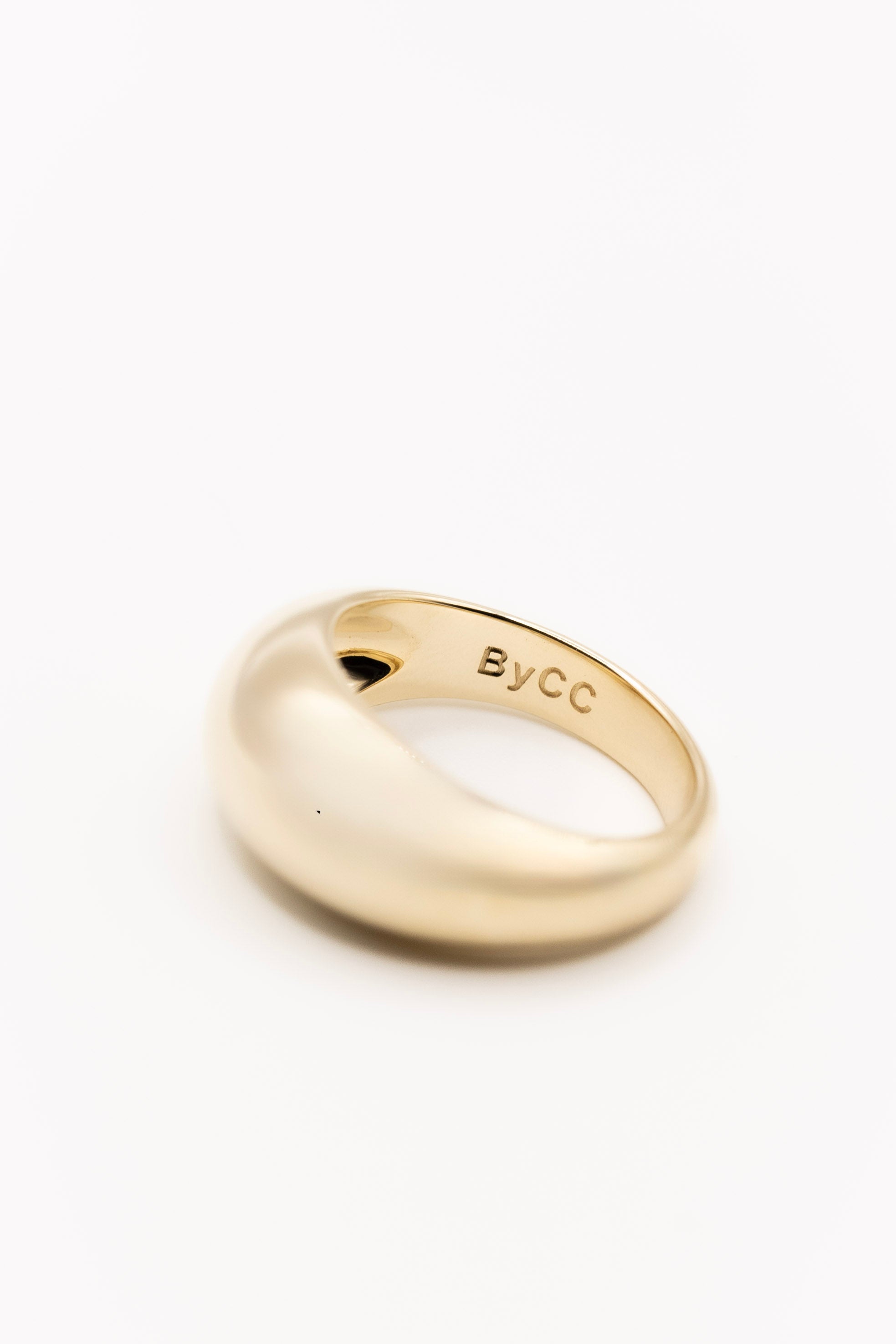 Gold ring with 'ByCC' engraving on a white background