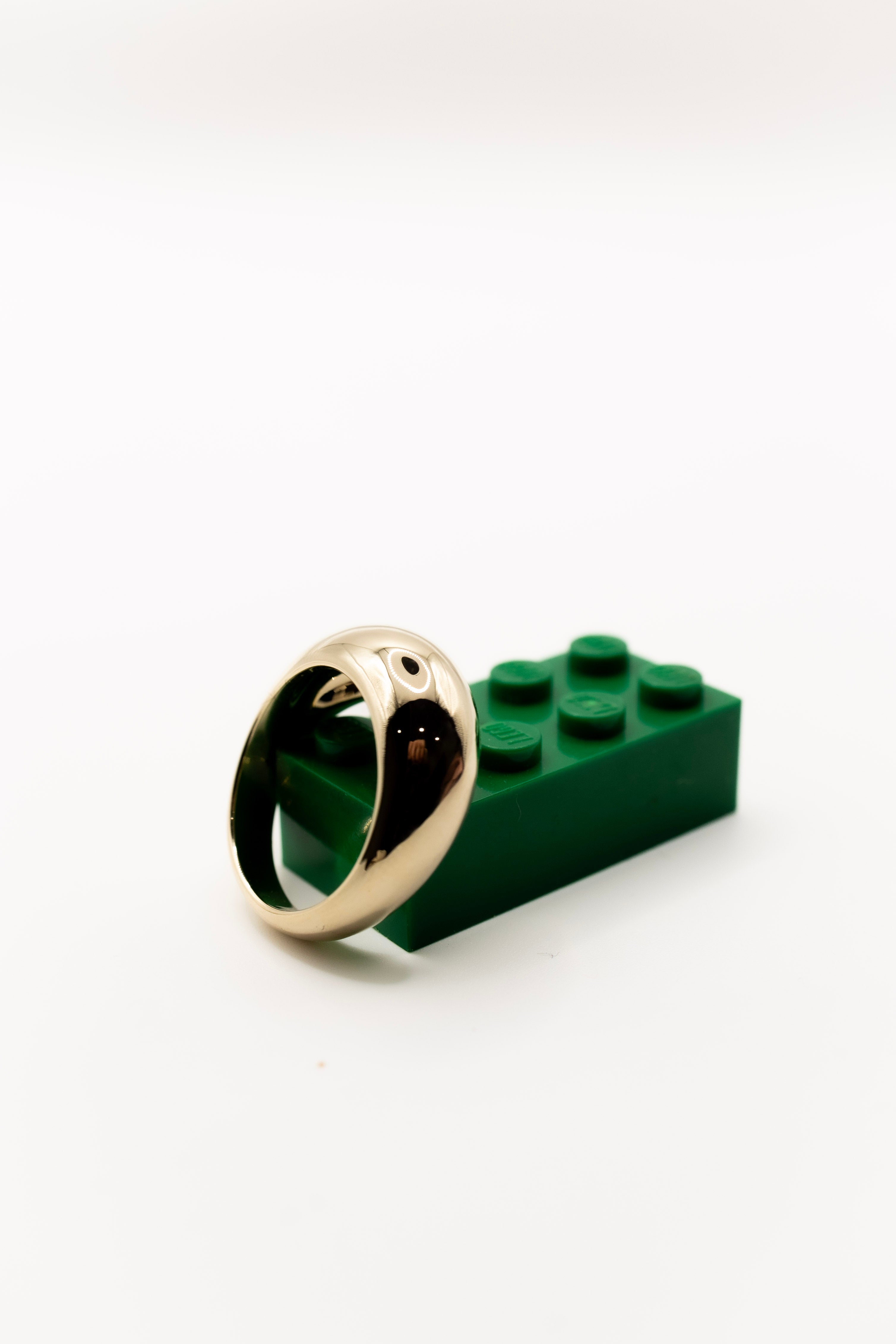 Gold dome ring on a green LEGO brick against a white background