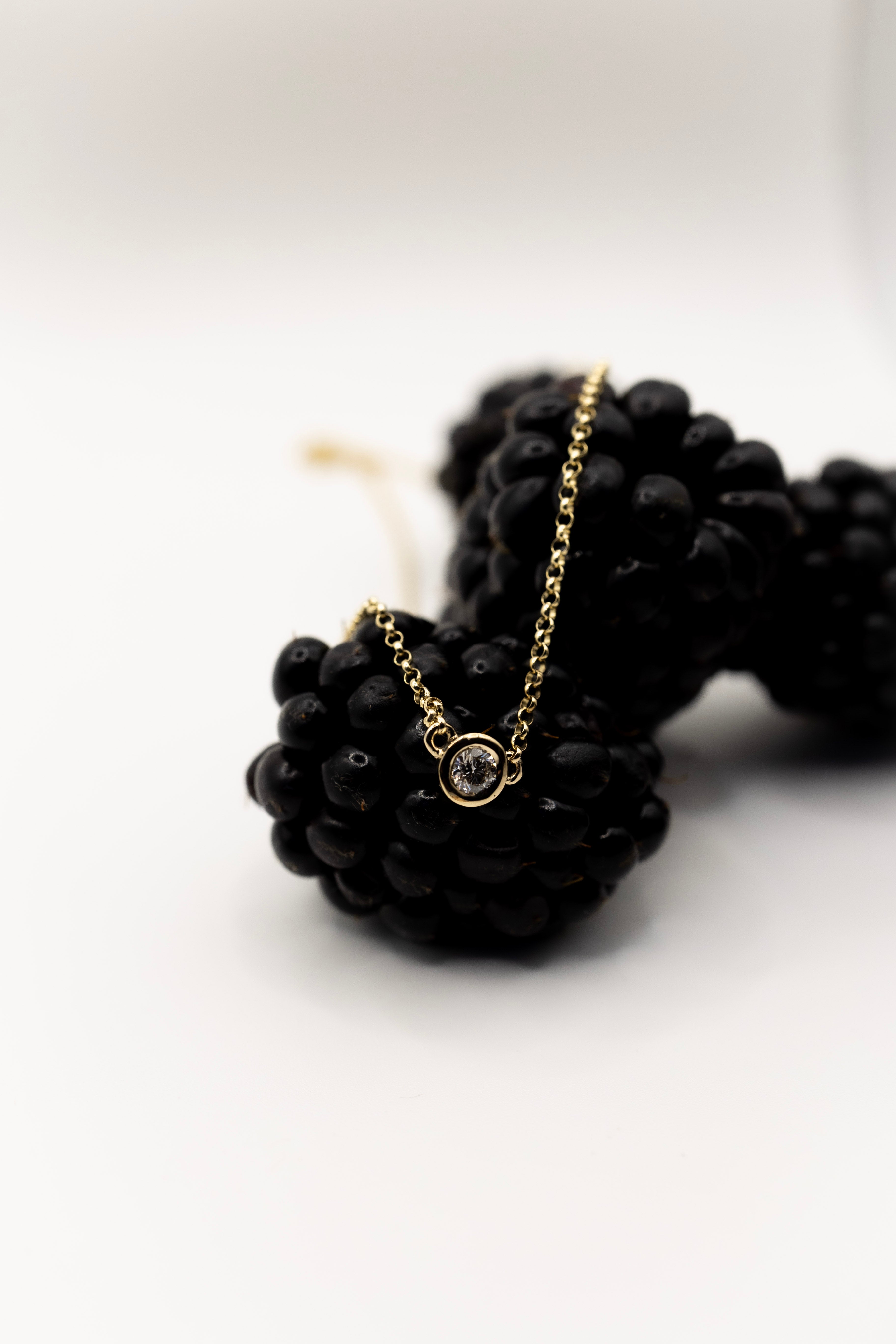 Yellow gold diamond necklace with a gold chain on a white background