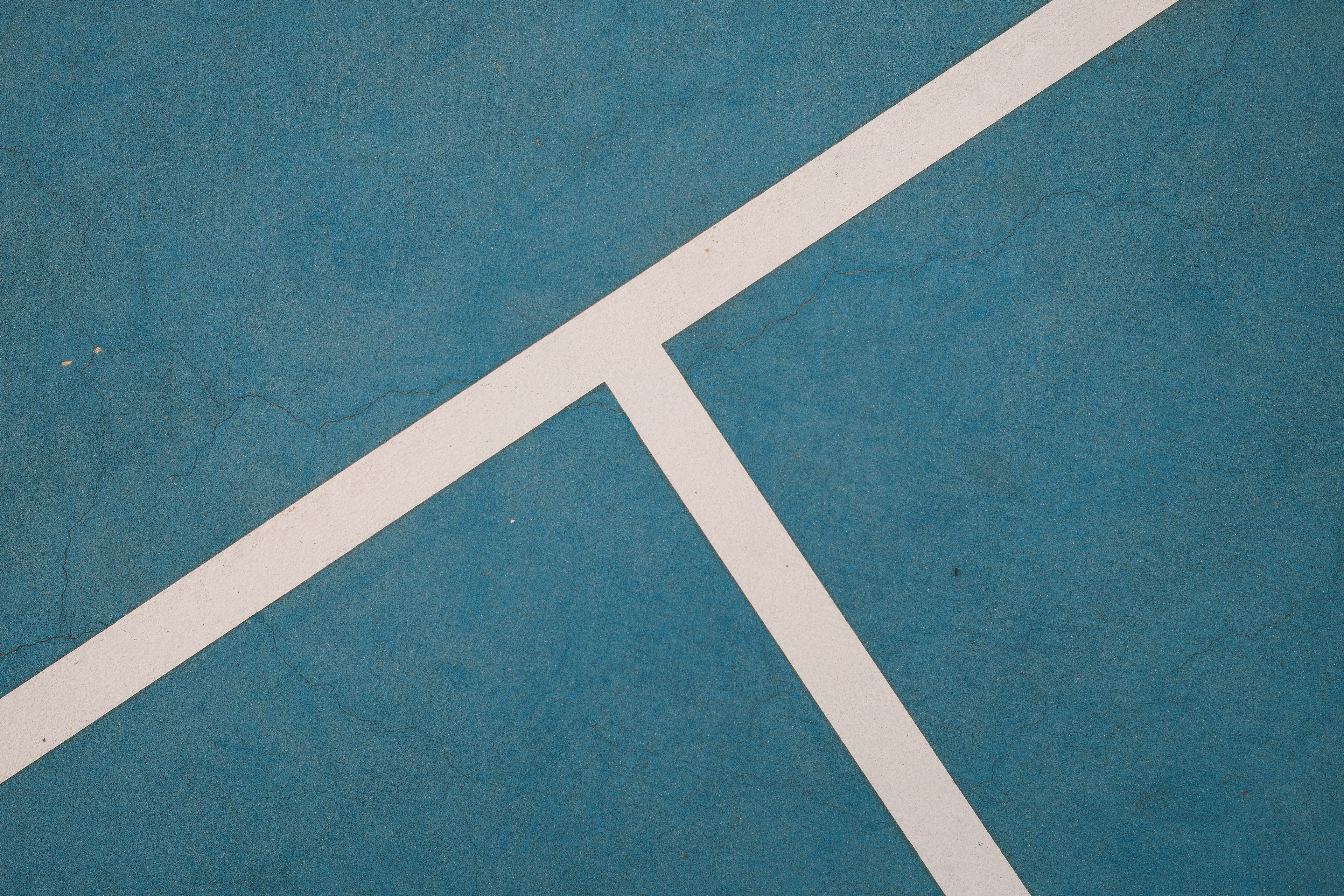 Close-up of a blue tennis court with white lines