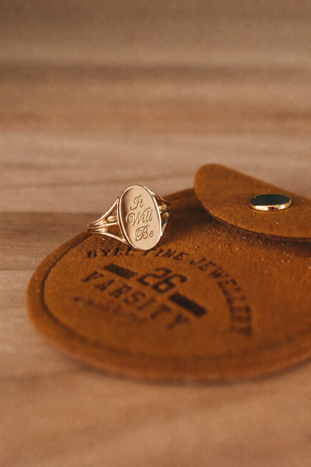 Gold ring on a brown leather patch with text
