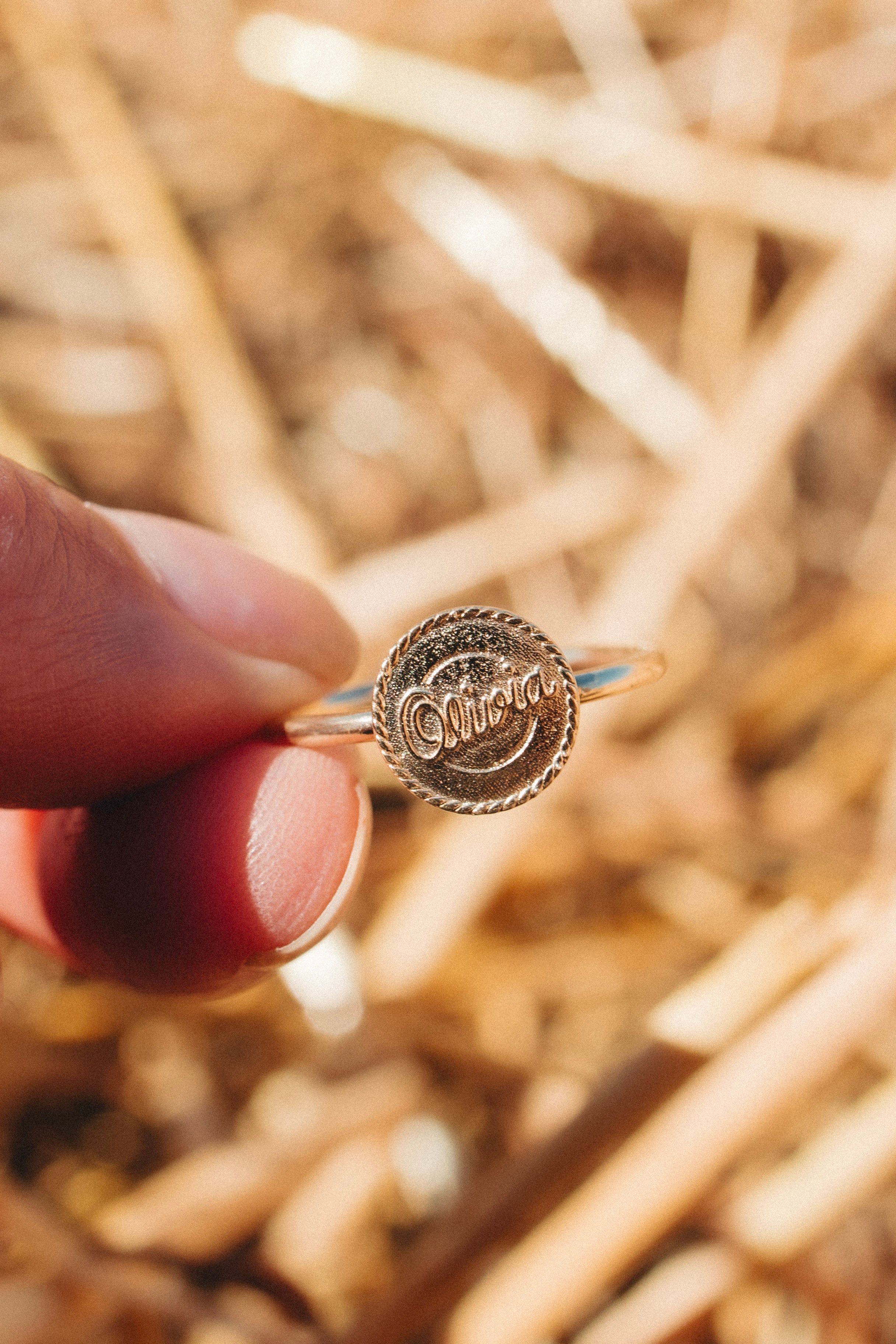 Western signet ring in solid gold styled alone on the hand, photographed in a rural NSW setting.