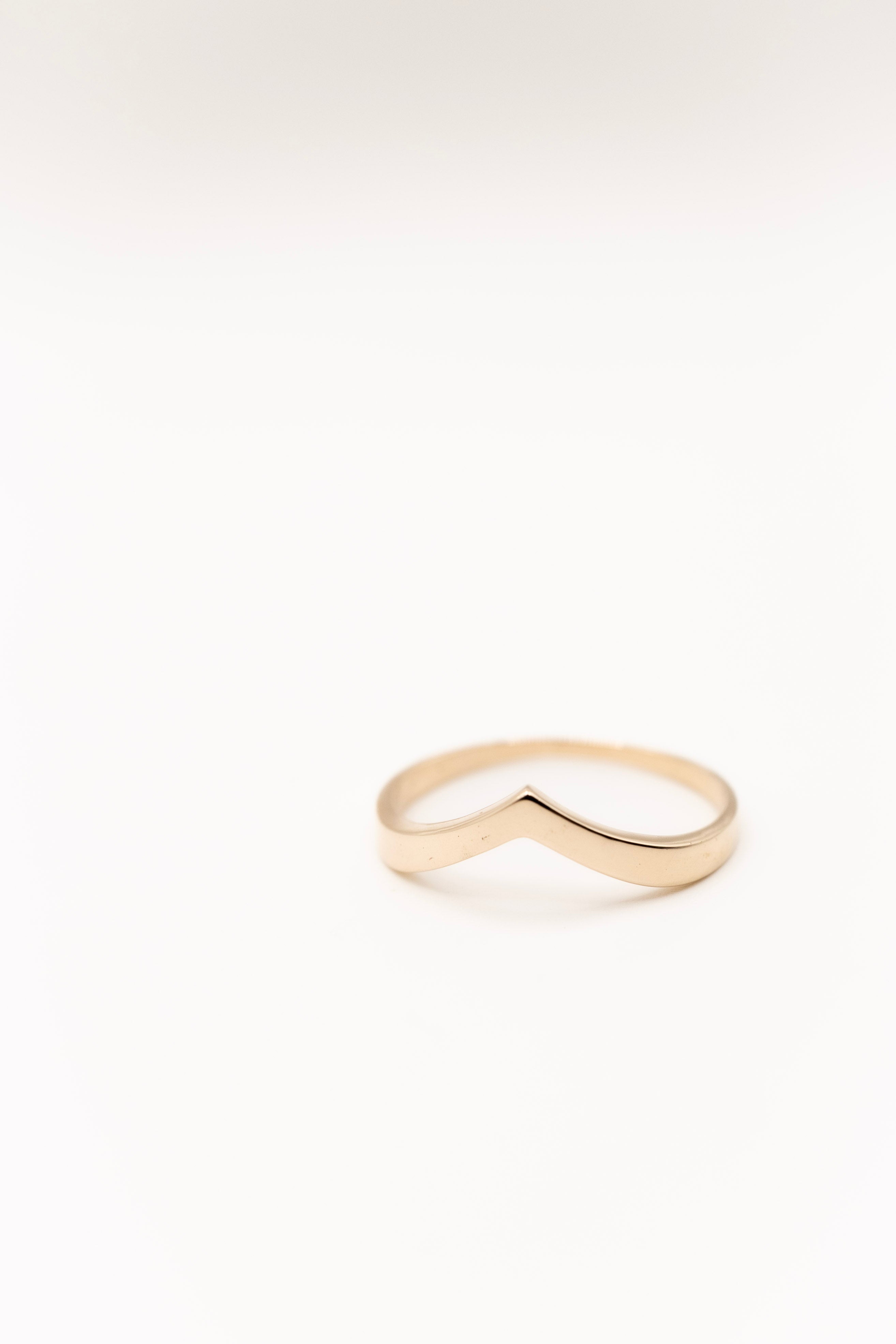 Gold ring with a wavy design on a white background