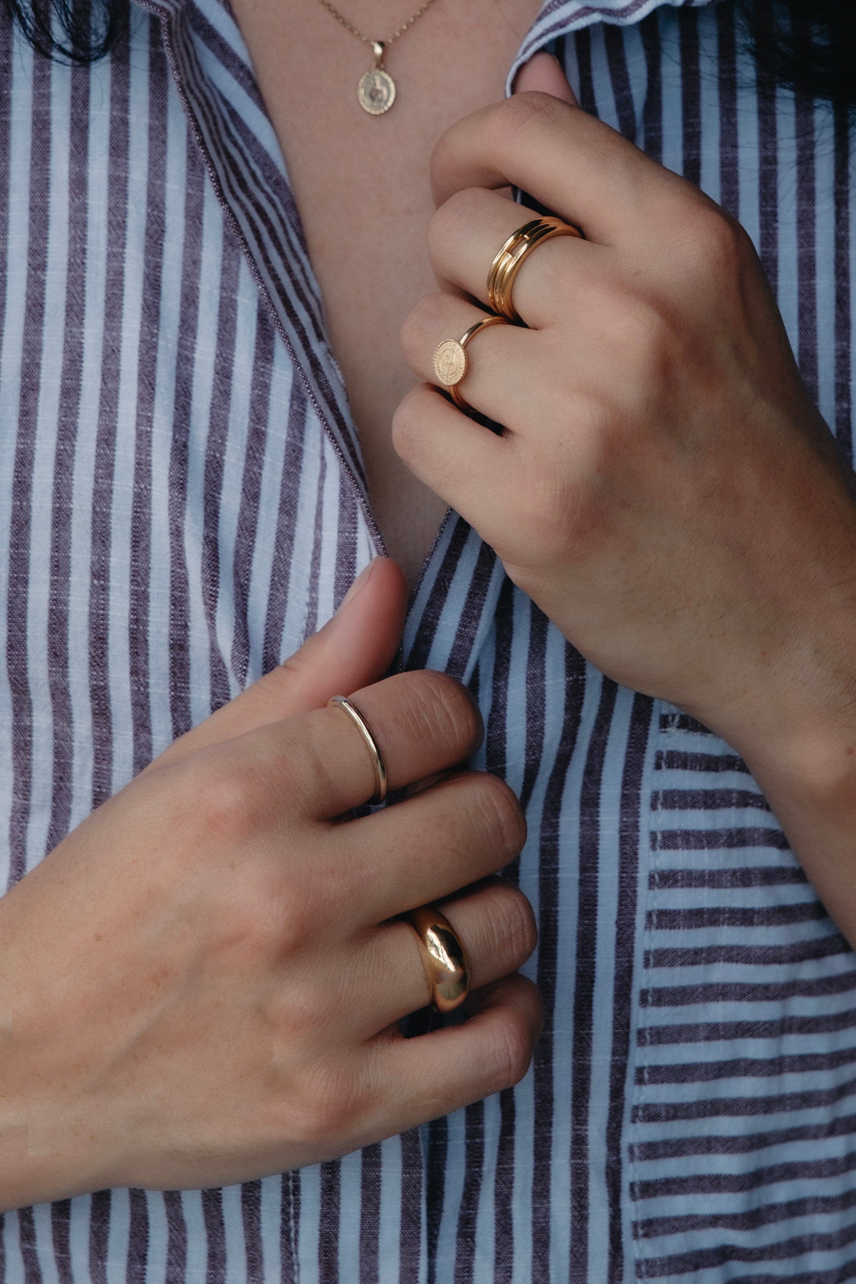 Plain solid gold band rings stacked on the hand and dome ring, designed for daily wear.