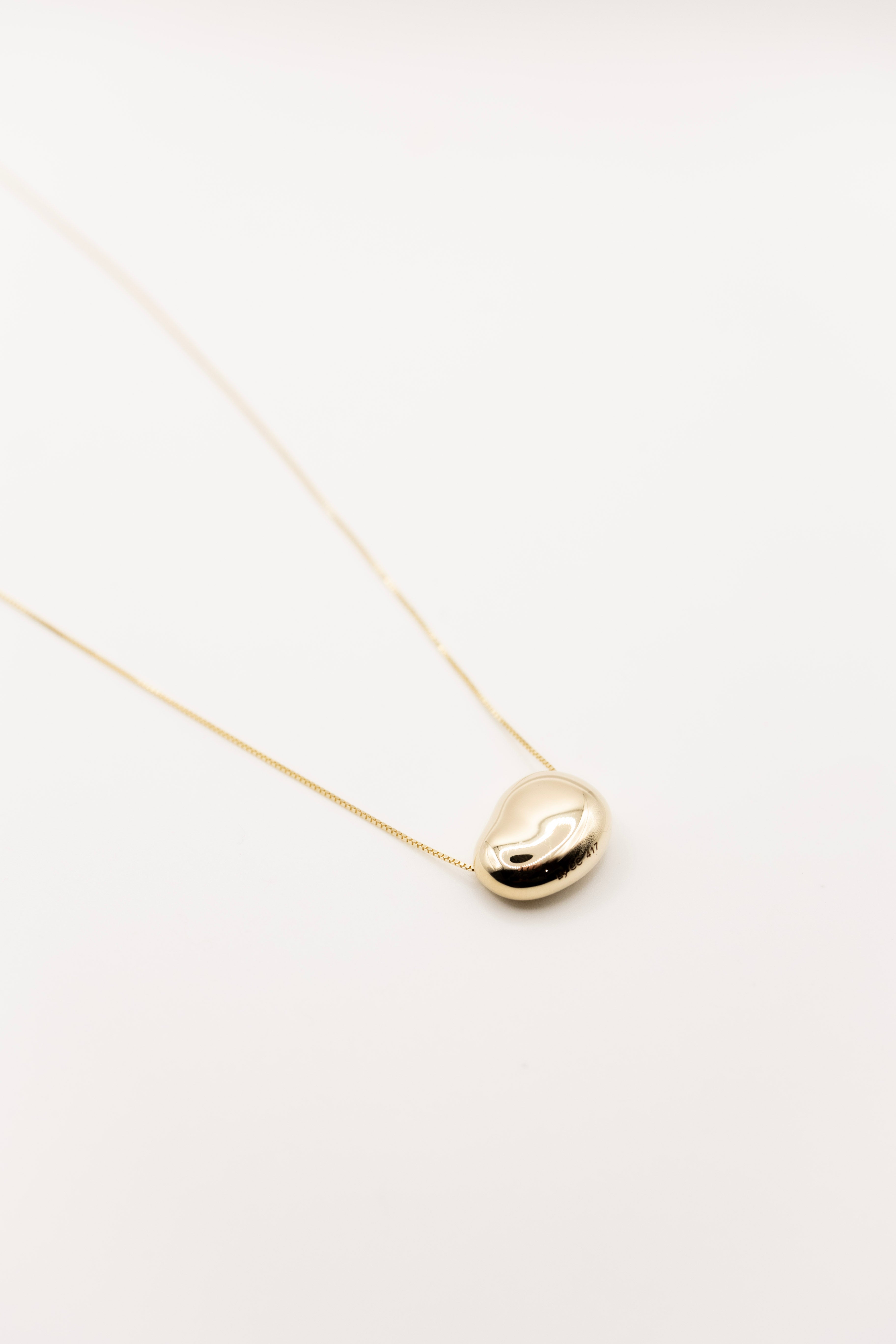 Gold necklace with a small pendant on a white background