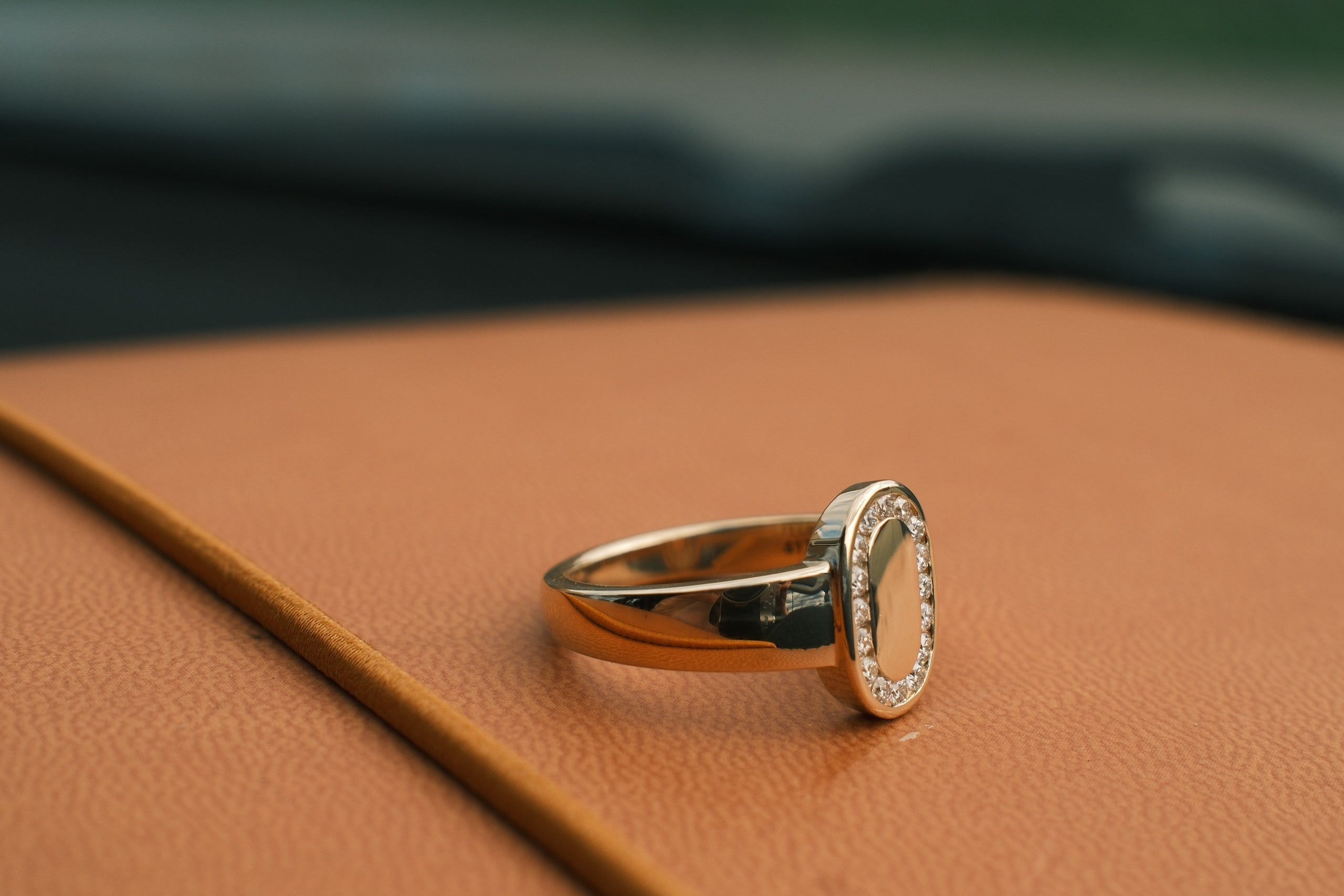 Gold ring with a diamond on a brown leather surface