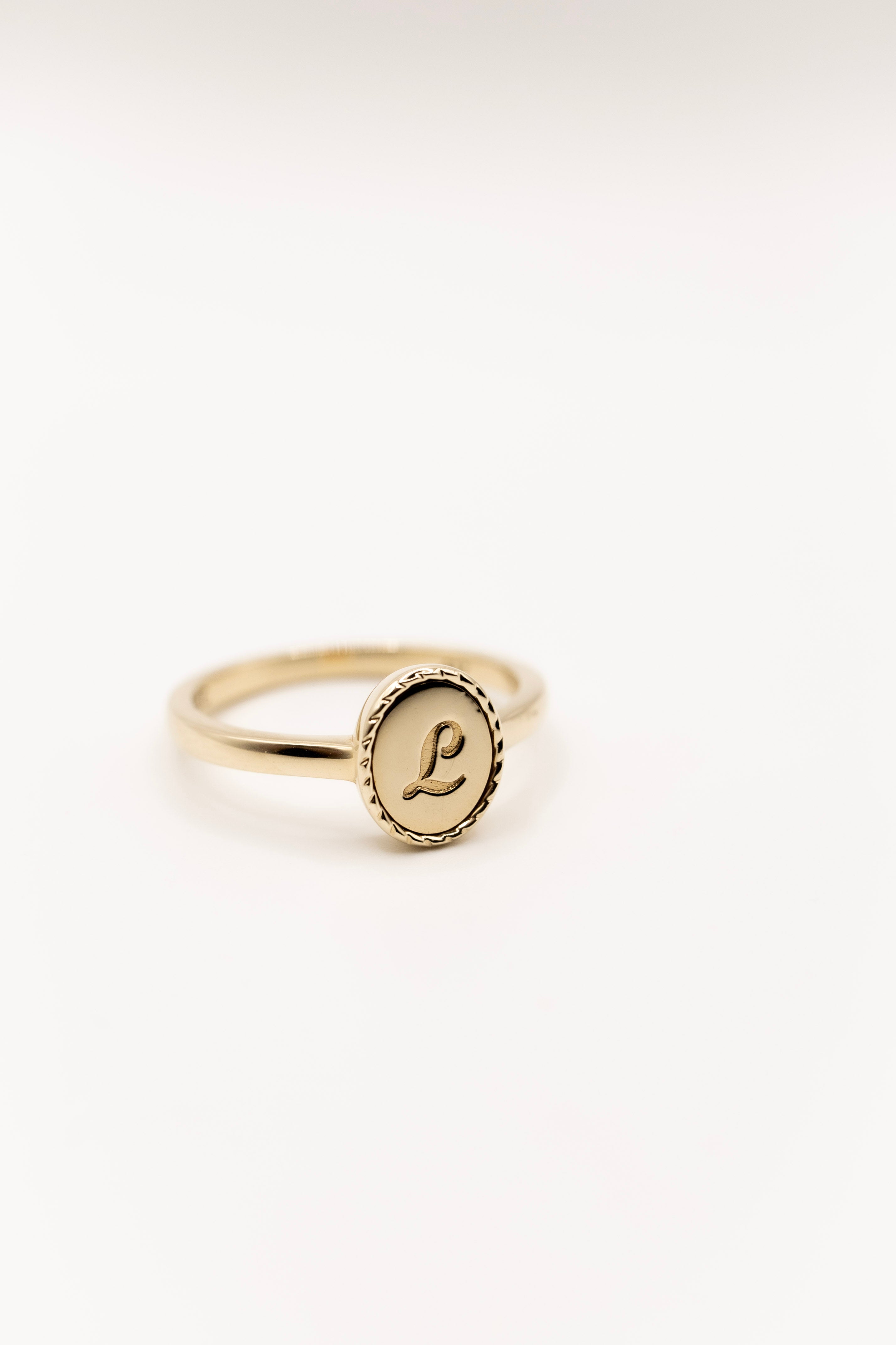Solid gold signet ring with a circular engraving on a white background